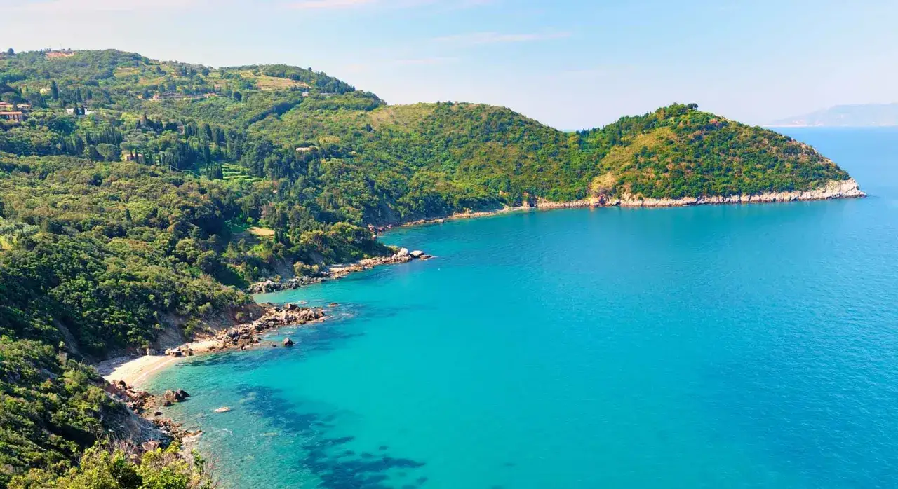 Costiera verdeggiante con mare turchese, rocce e una piccola spiaggia, un vero angolo di paradiso, una spiaggia di Bengodi.