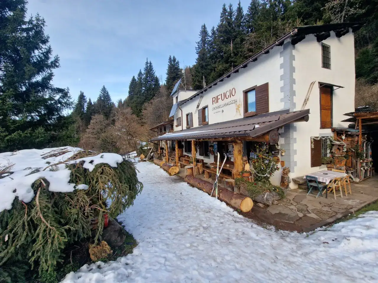 Rifugio Cimon della Bagazza, un luogo accogliente con rifugi aperti in inverno in Lombardia, circondato da neve e alberi.
