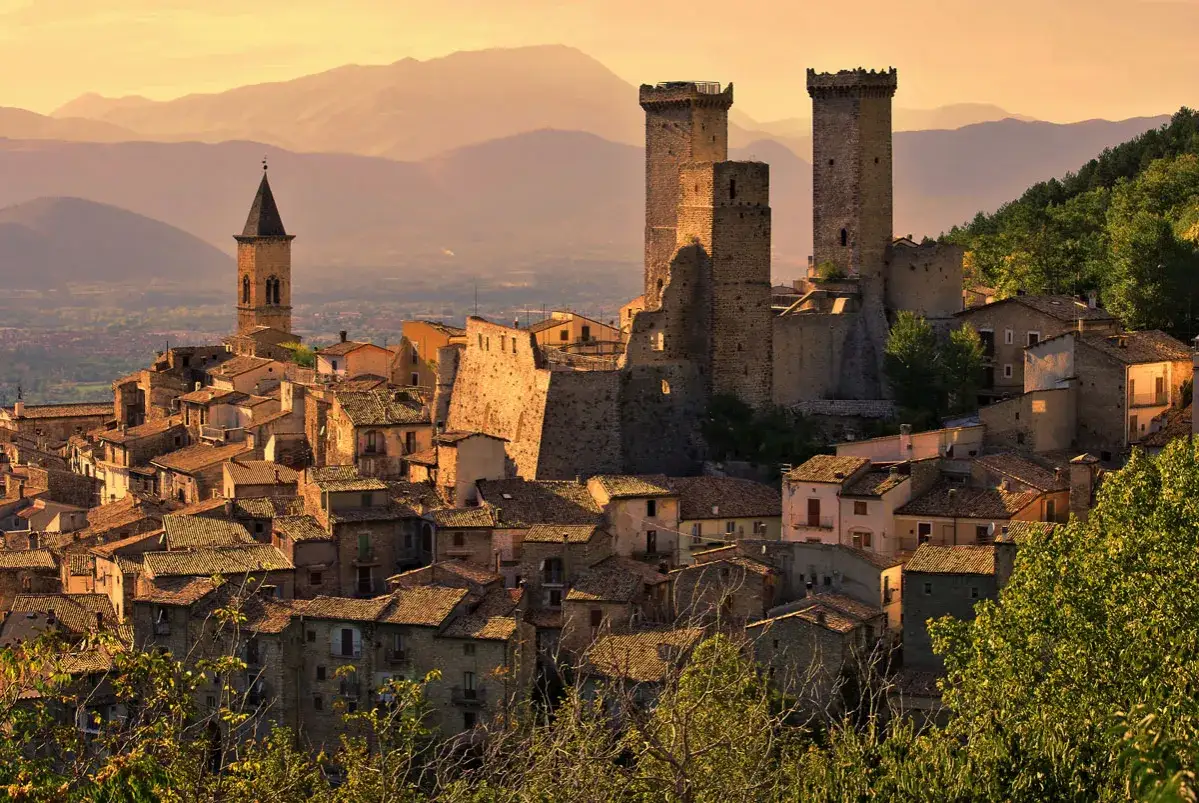 Antico castello e campanile dominano i borghi abruzzesi sul mare, immersi nella luce dorata del tramonto.