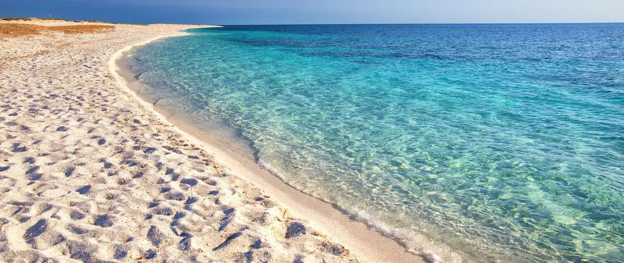 Spiaggia pop corn in Sardegna, con sabbia bianca e finissima che ricorda i chicchi di mais, bagnata da un mare cristallino dalle sfumature turchesi.
