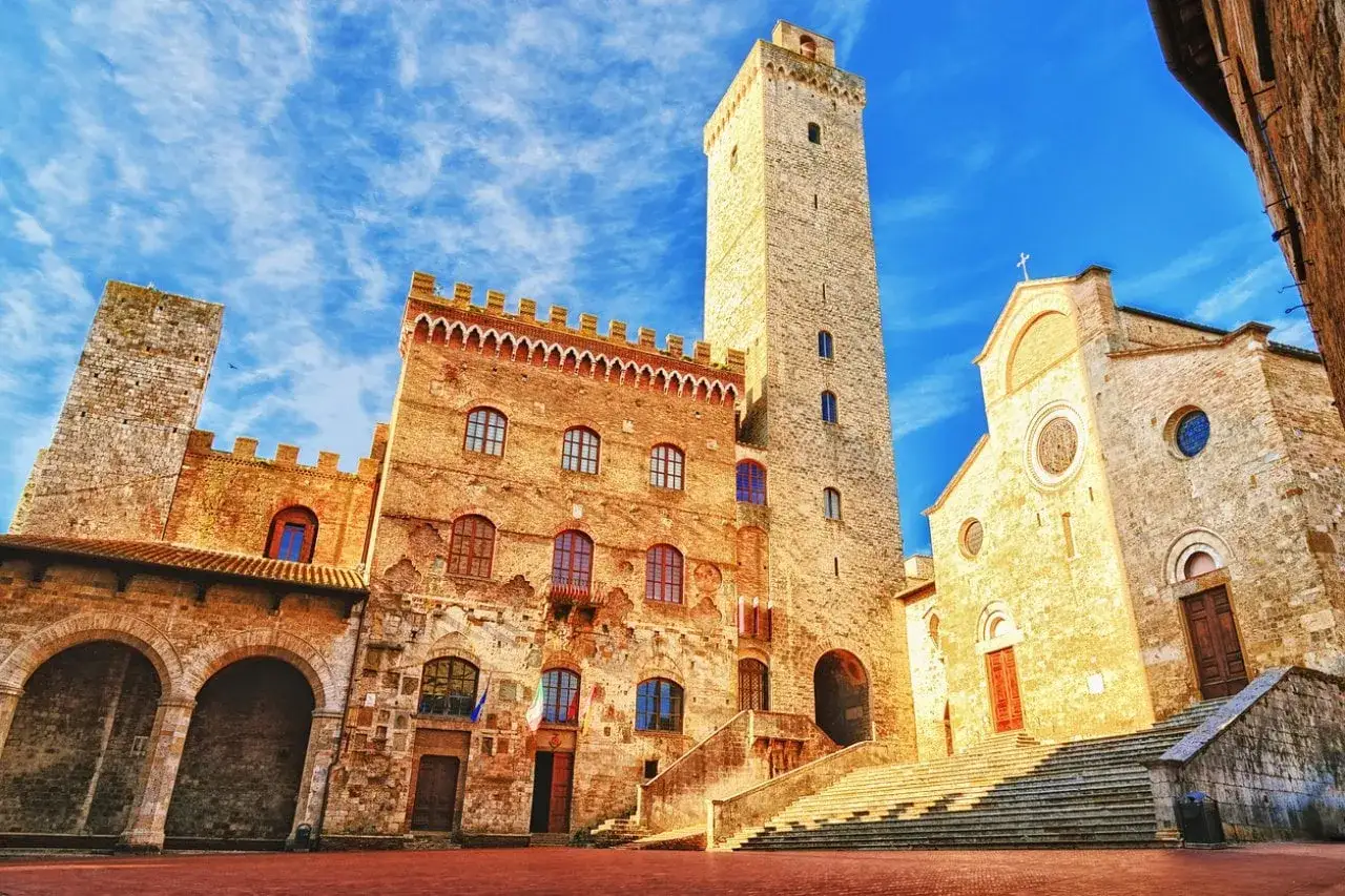 Torri medievali e chiese a San Gimignano, Siena, sotto un cielo azzurro vibrante.