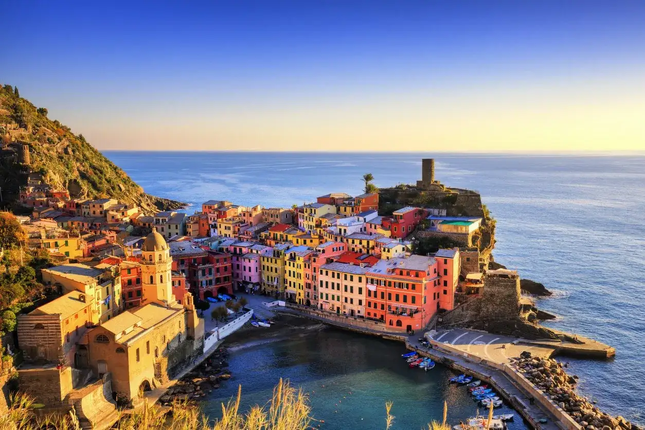 Colorate case aggrappate alla scogliera, una città sul mare nord Italia baciata dal sole.