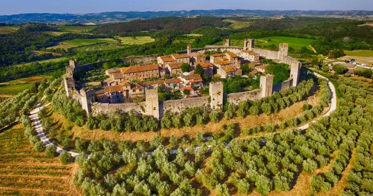 Borghi medievali toscana, un castello fortificato su una collina, circondato da ulivi e vigneti, con dolci colline sullo sfondo.