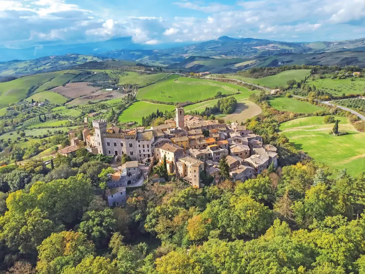 Borgo medievale su una collina, circondato da verdi colline toscane. Perfetto per una gita fuori porta toscana da sogno.