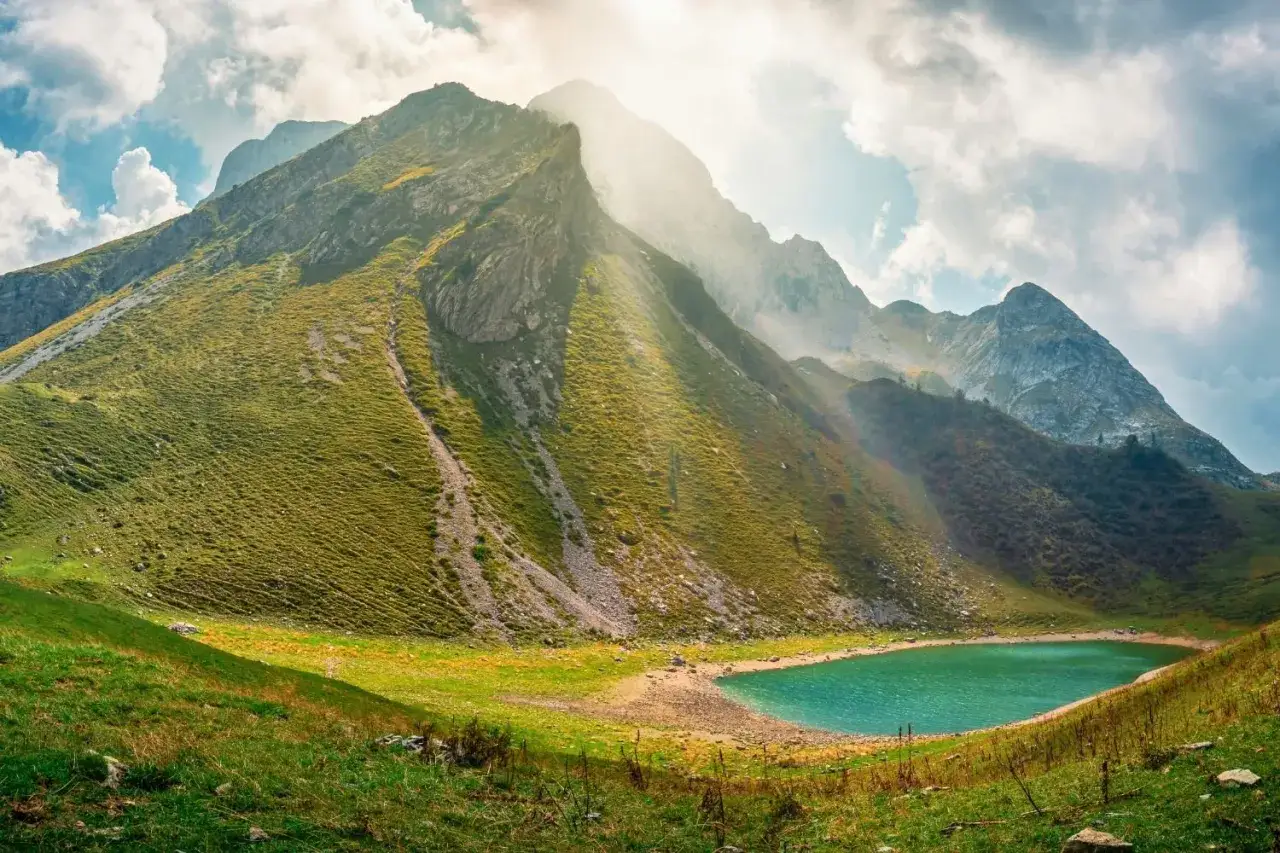 Un lago alpino turchese ai piedi di una montagna verdeggiante, un paesaggio da sogno vicino Milano.