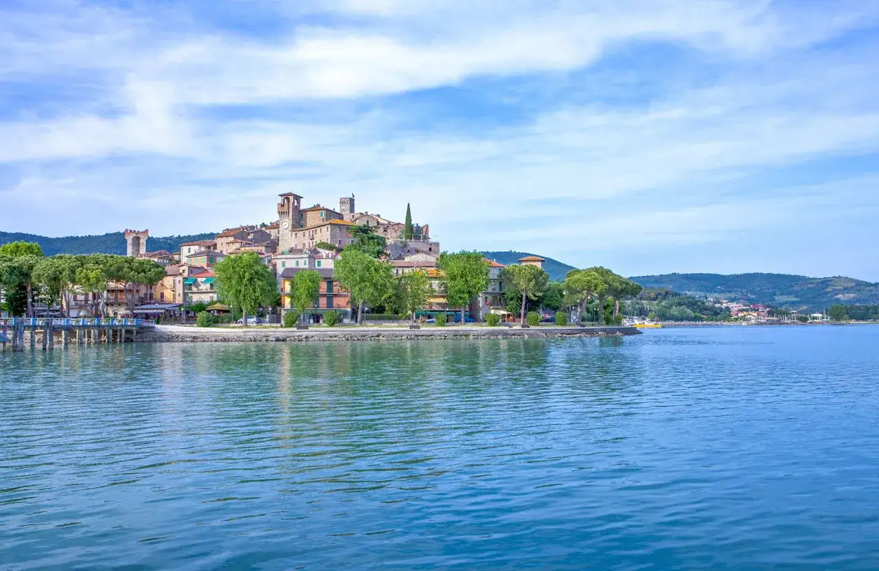 Il borgo più bello del Lago Trasimeno, con le sue case colorate e torri antiche, si specchia nelle acque azzurre.