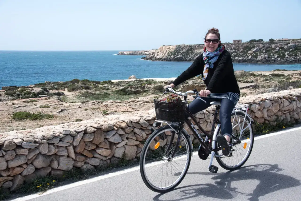 Donna in bicicletta lungo la costa, un'idea per cosa vedere a Favignana in un giorno.