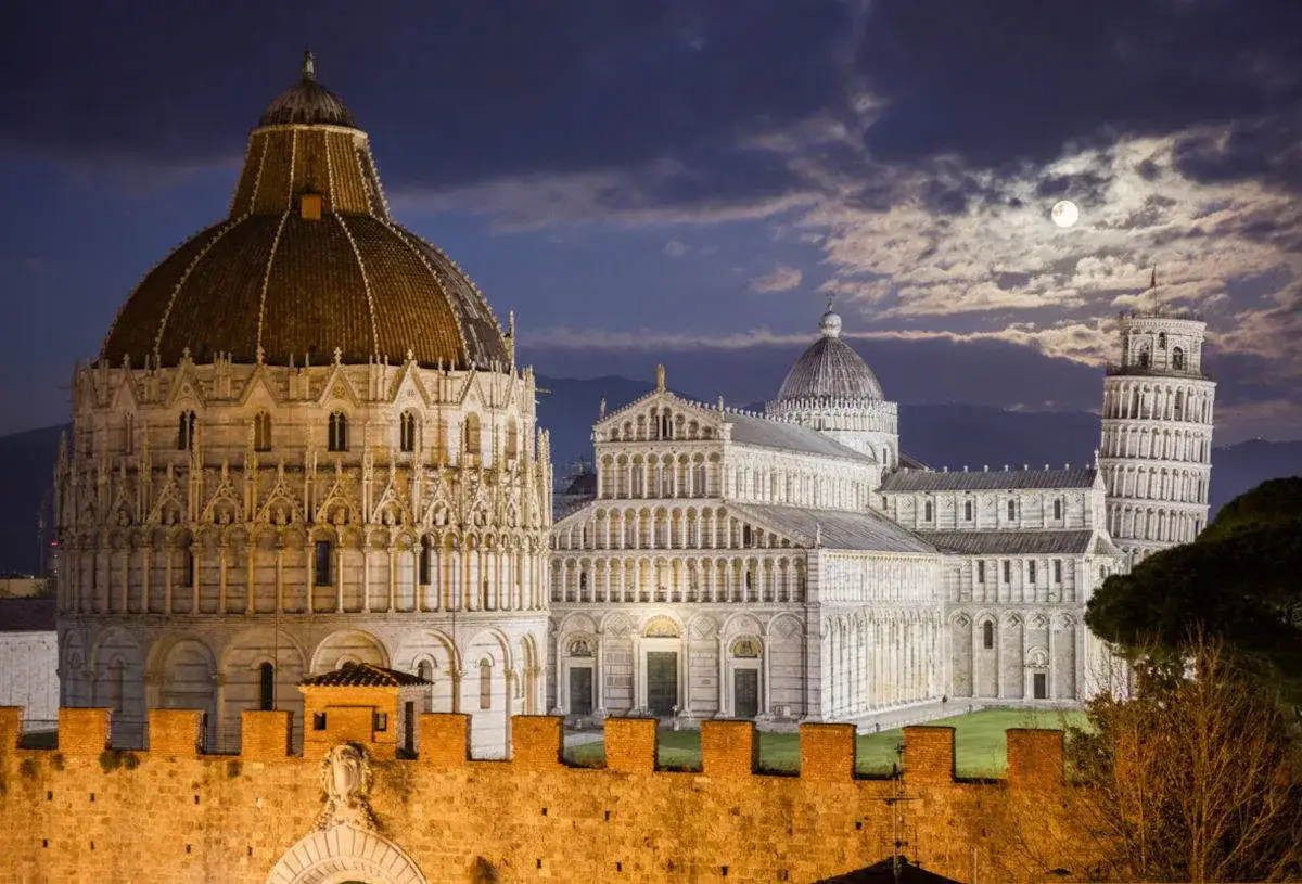 Piazza dei Miracoli di notte: Duomo, Battistero e Torre Pendente sotto la luna. Un'ottima idea per cosa vedere a Pisa in un giorno.