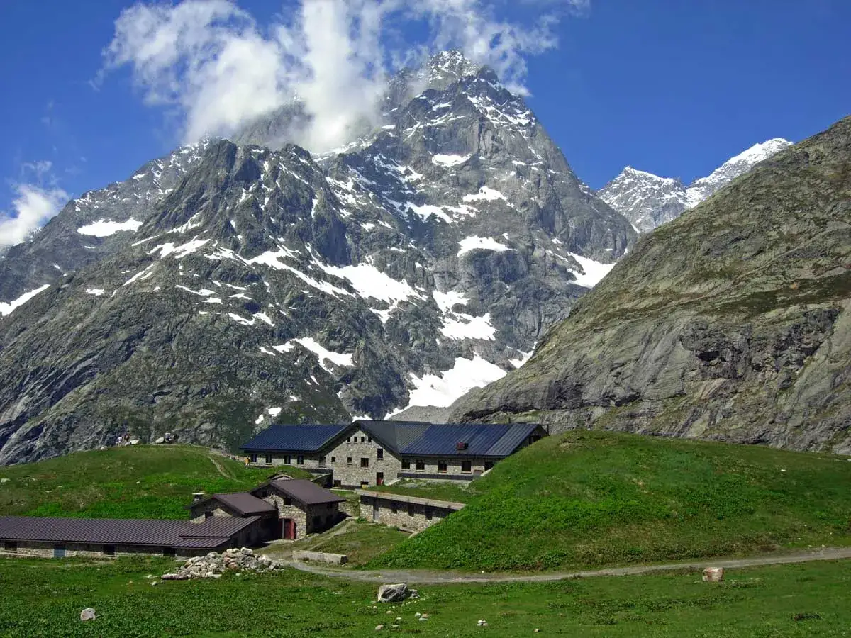 Rifugi in pietra ai piedi di montagne innevate, ideali per val ferret passeggiate facili.