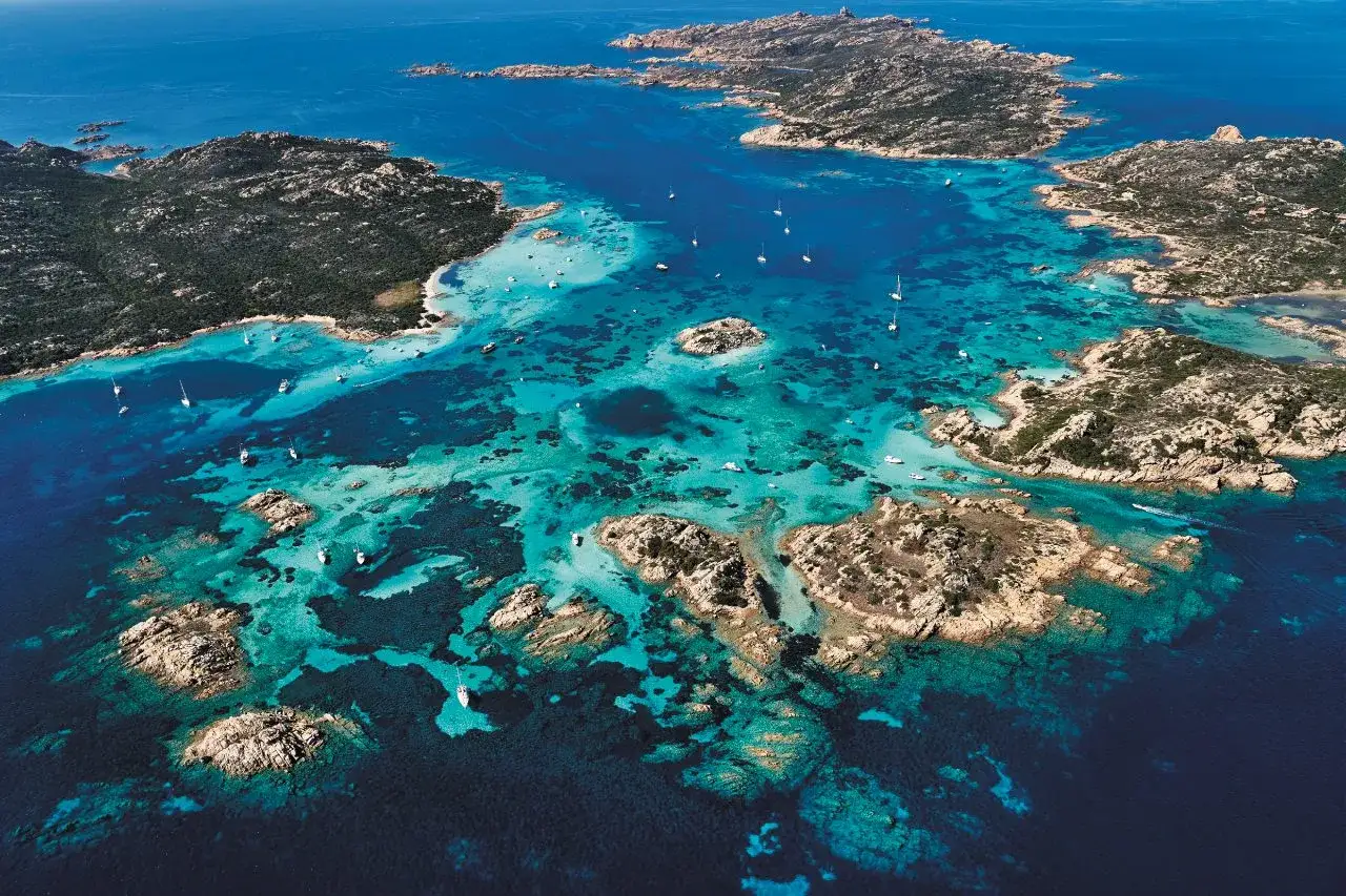 Arcipelago de La Maddalena, con acque cristalline e isole rocciose, dove si trova la Maddalena, punteggiato da barche a vela.
