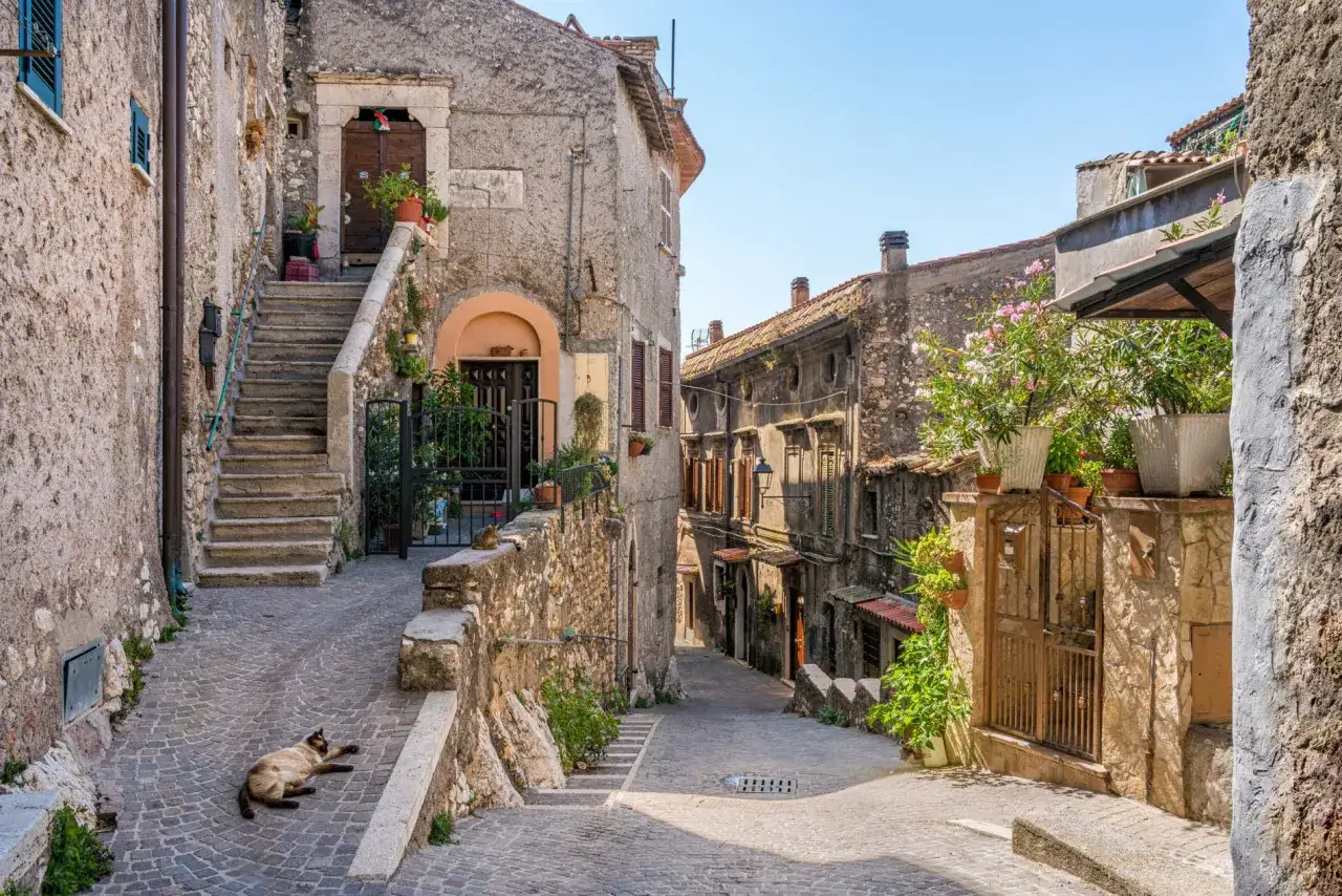Un gatto si gode il sole in un vicolo acciottolato, tra le case di pietra di uno dei tanti borghi italiani da visitare.