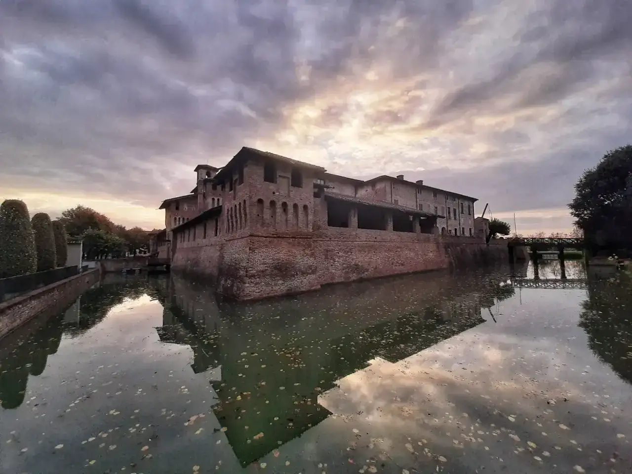 Castello medievale lombardo con fossato, un gioiello tra i borghi medievali Lombardia da visitare, riflesso sull'acqua al tramonto.