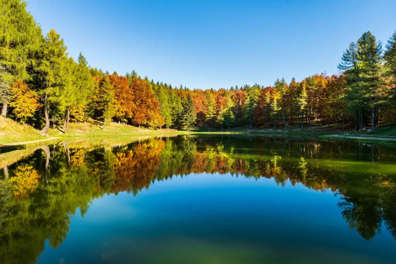 Lago alpino con riflessi autunnali, ideale per escursioni in Emilia Romagna.