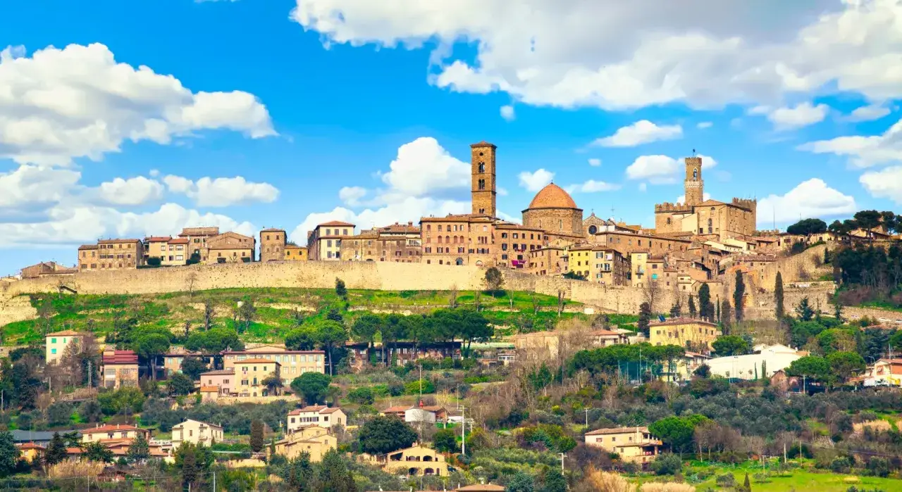 Panoramica di Volterra, con torri medievali e case in pietra su una collina verde. Ideale per scoprire cosa vedere a Volterra in mezza giornata.