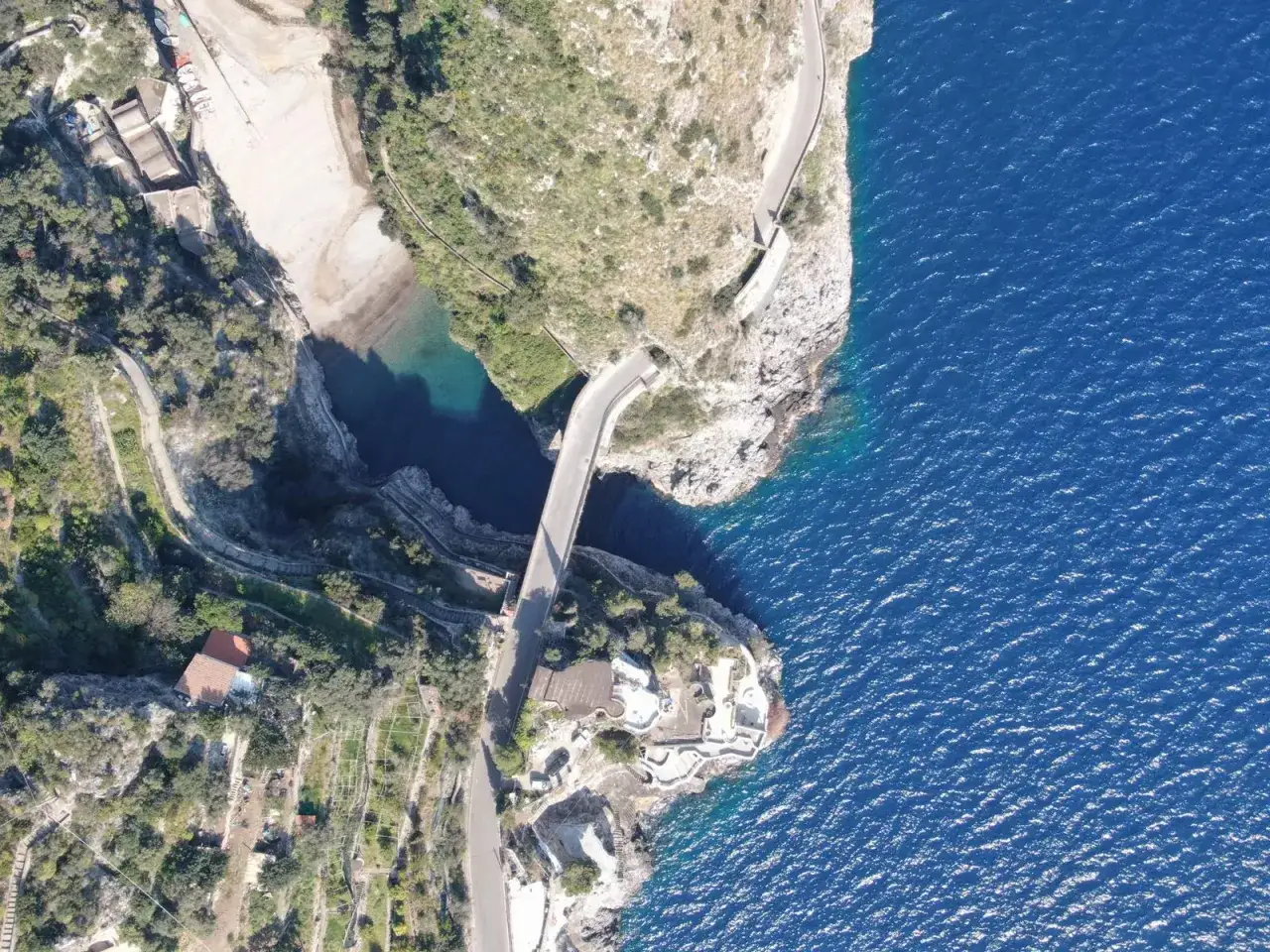 Vista aerea di un ponte che attraversa un fiordo, con il mare blu intenso e la vegetazione che caratterizzano il furore costiera amalfitana.