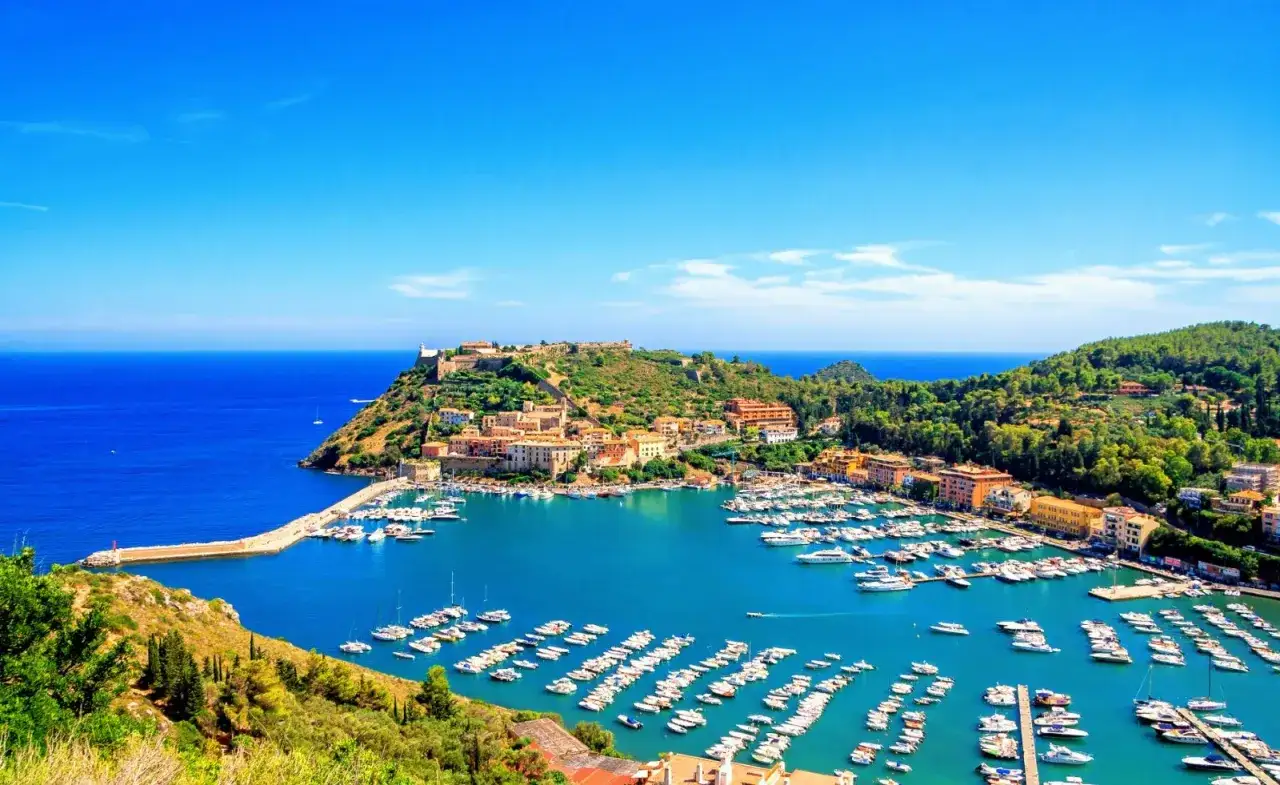 Porto Santo Stefano, con il suo porto pieno di barche e le case colorate arroccate sulla collina, si affaccia sul blu intenso del mare.
