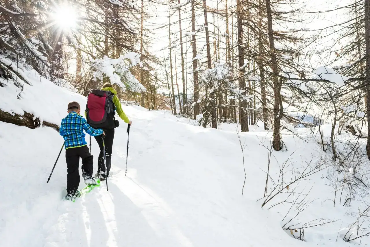 Due persone camminano sulla neve con le ciaspole, scoprendo cosa sono e come permettono di muoversi agilmente in inverno.