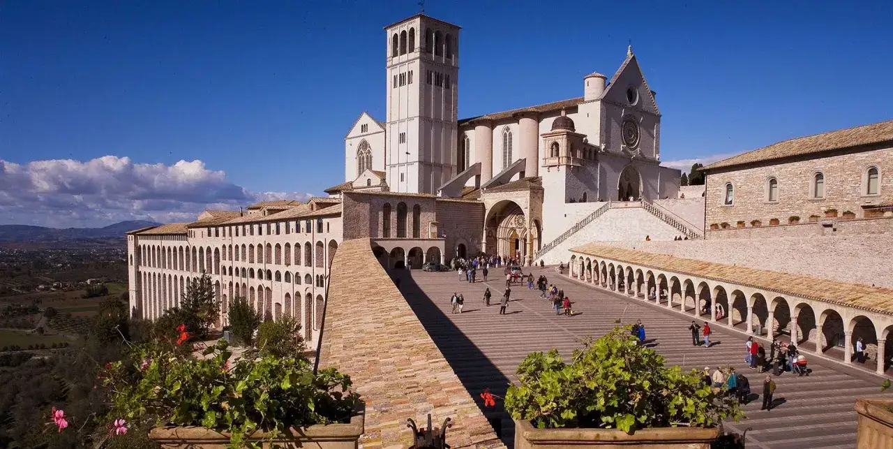 Basilica di San Francesco ad Assisi, un luogo imperdibile per chi visita cosa vedere ad Assisi in un giorno. La piazza antistante è animata da turisti.