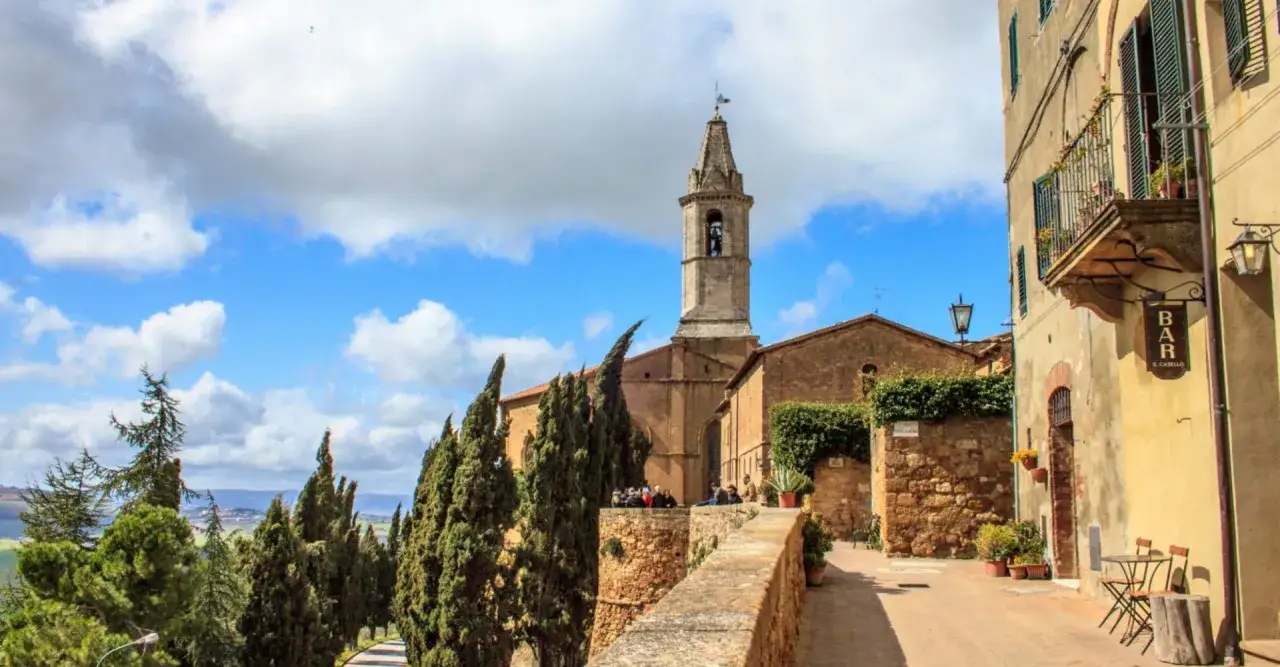 Una gita domenicale toscana in un borgo con un campanile, cipressi e un bar.