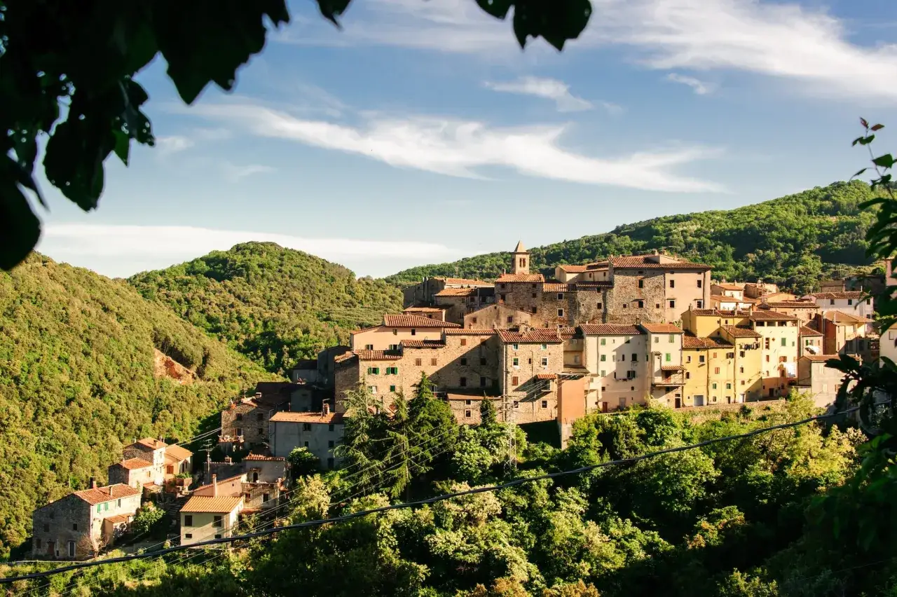 Sassetta, un borgo toscano incastonato tra colline verdi. Case in pietra e tetti rossi si affacciano su un paesaggio mozzafiato, un invito a scoprire cosa vedere.