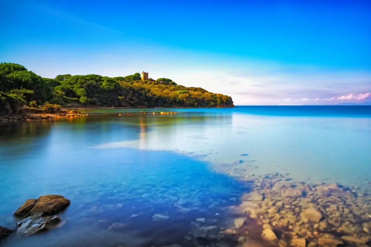 Torre medievale su promontorio verdeggiante, con acque cristalline che lambiscono le punta ala spiagge più belle.