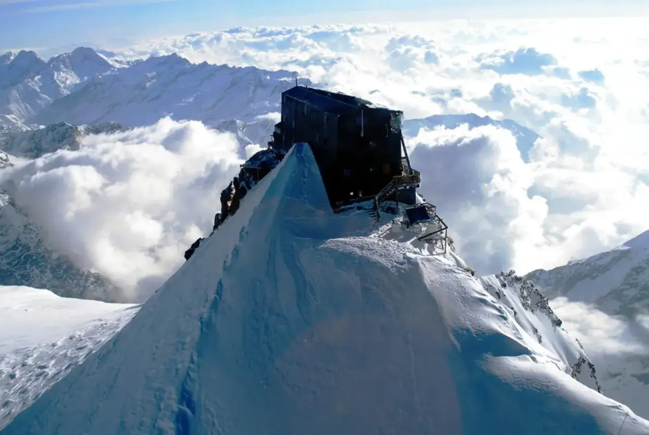 Il rifugio più alto d'Italia, incastonato su una vetta innevata, domina un mare di nuvole e montagne.