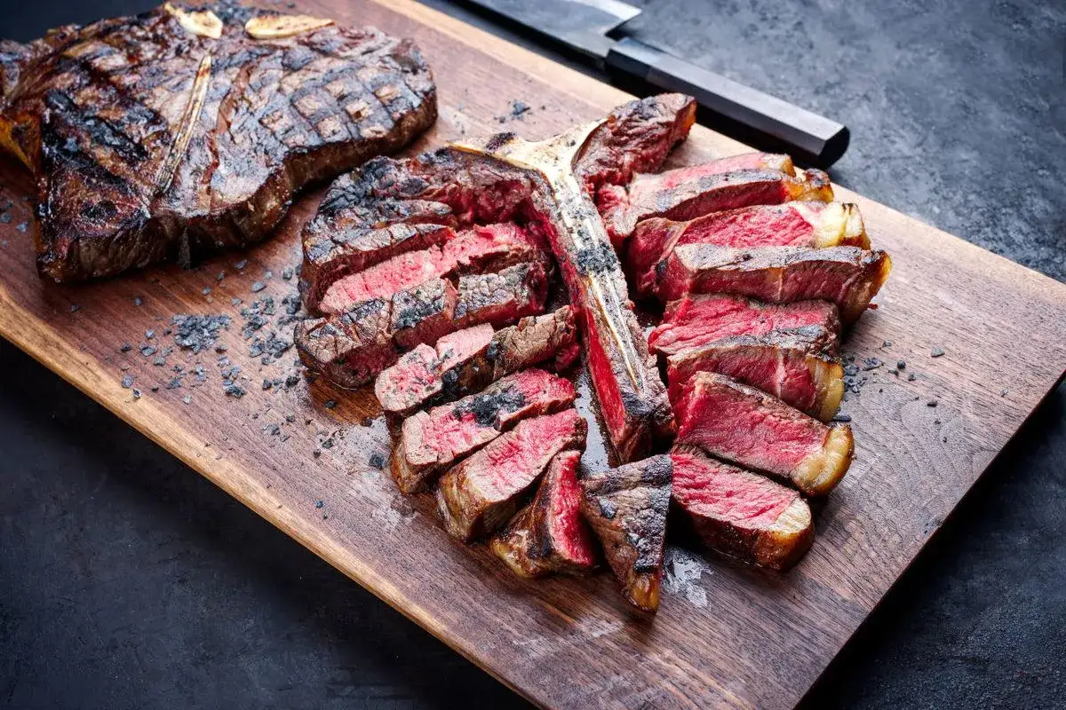 Bistecca fiorentina a Firenze, succulenta e cotta alla perfezione, servita su tagliere di legno con sale grosso.