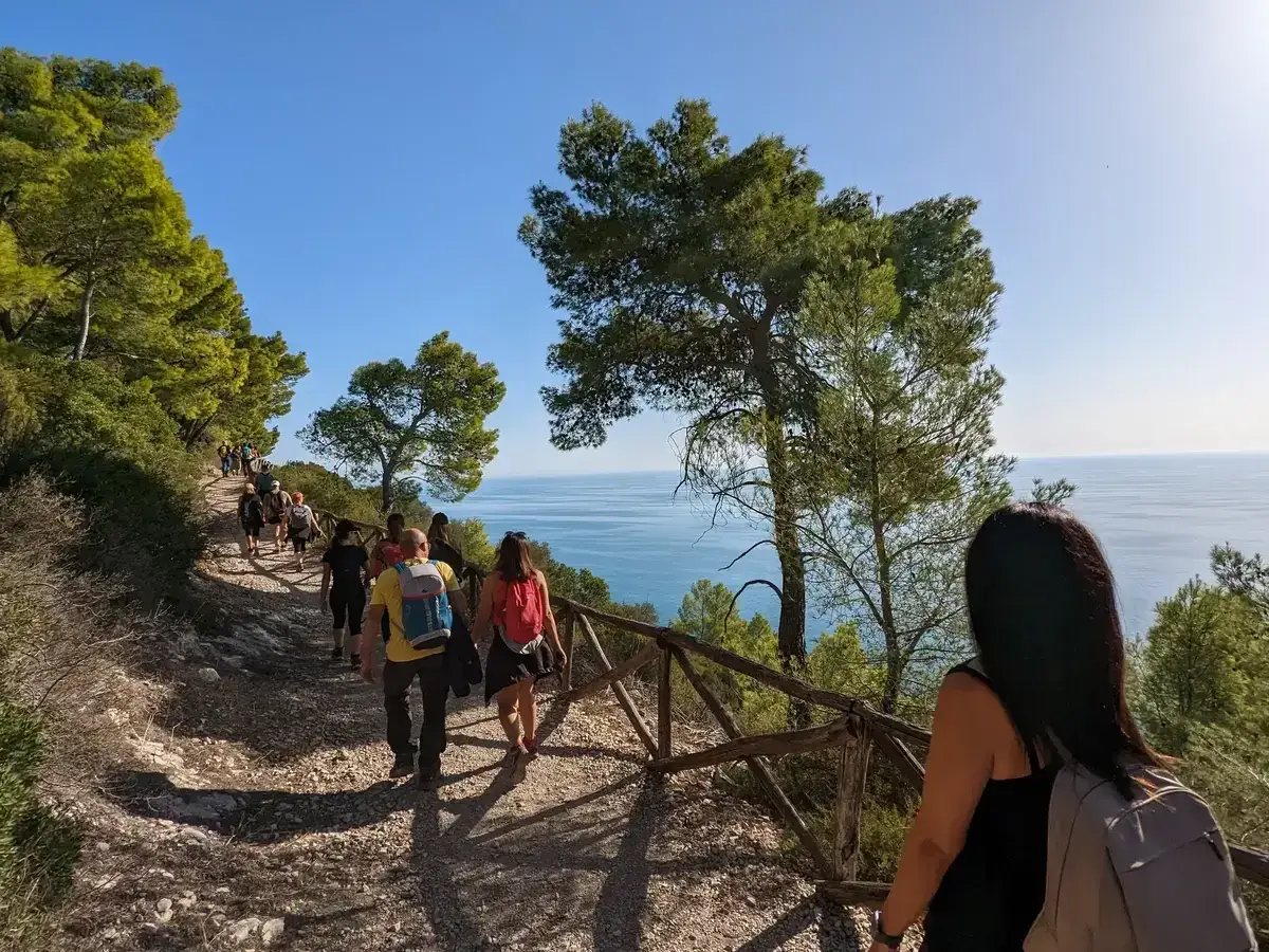 Un gruppo di persone fa escursioni in Puglia su un sentiero panoramico con vista sul mare.