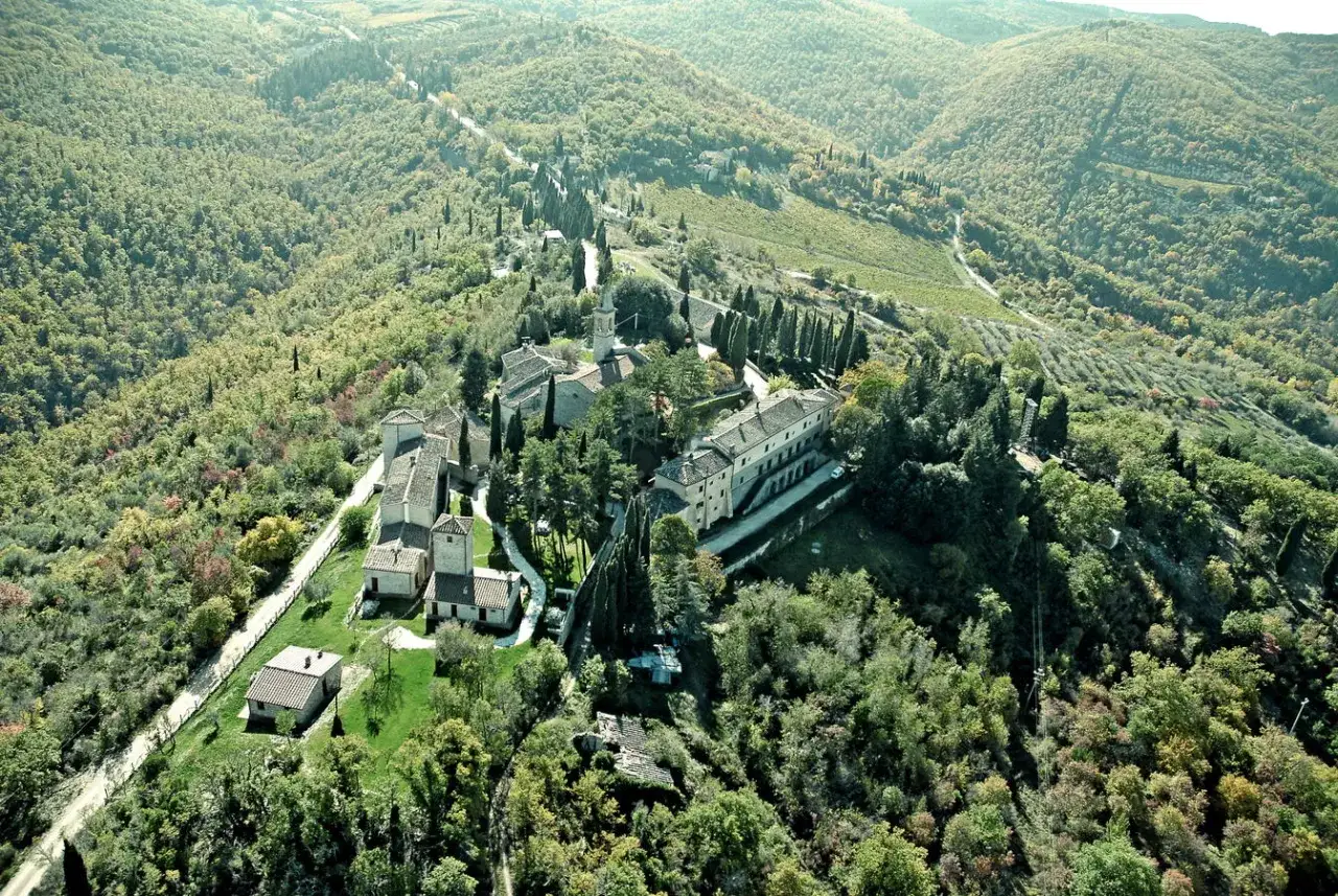 Borgo di San Donato in Poggio immerso nel verde delle colline toscane, con edifici storici e cipressi.