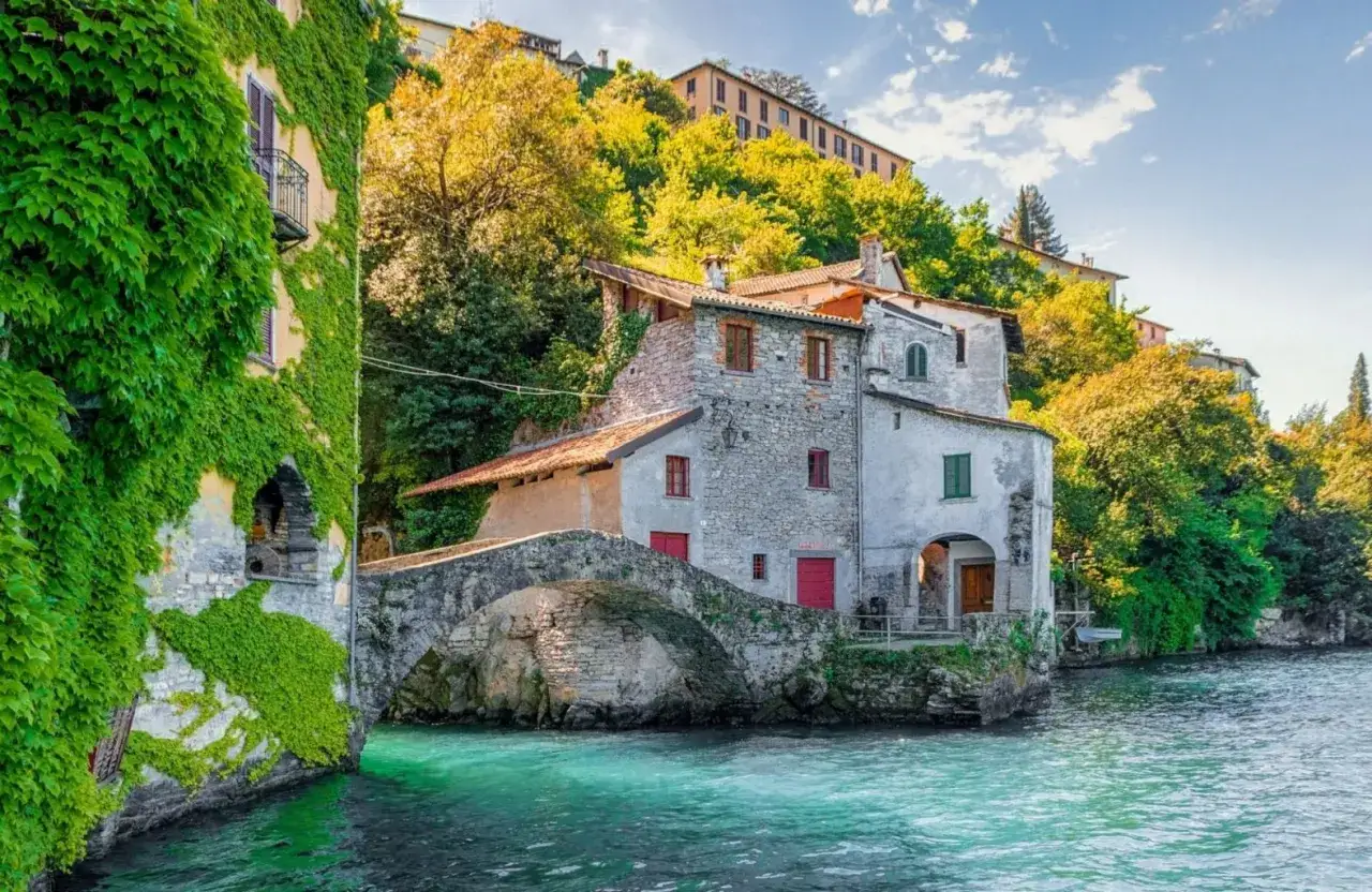Un borgo pittoresco con case in pietra e edera, un ponte ad arco sull'acqua turchese. Un angolo incantevole da scoprire tra le cose da vedere in Lombardia.