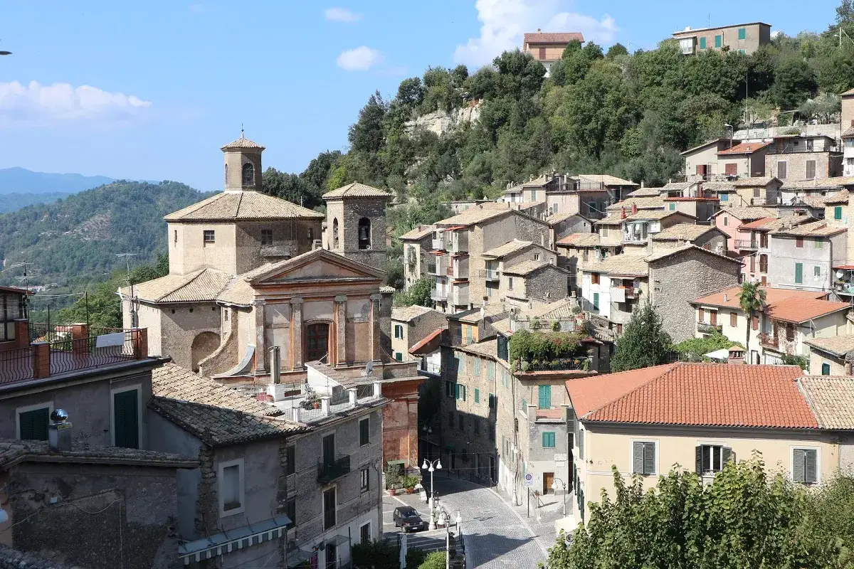 Un panorama del subiaco centro storico con chiese, case in pietra e tetti rossi, immerso nel verde delle colline.