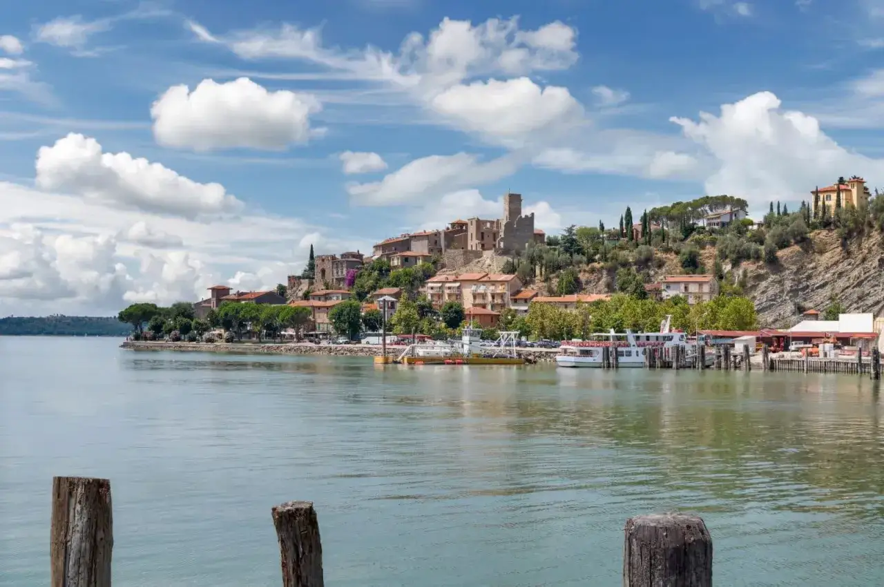 Il centro storico di Passignano sul Trasimeno si affaccia sul lago, con case colorate e un castello in cima alla collina.