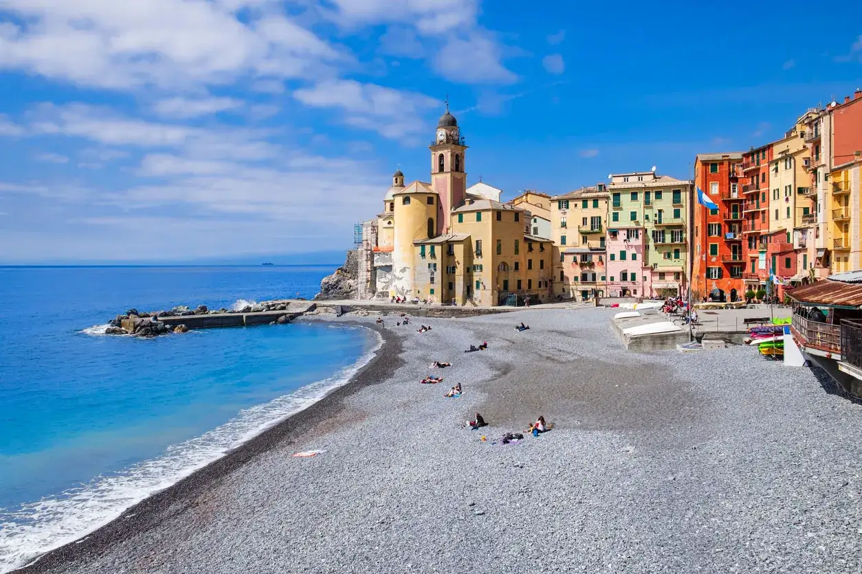 Camogli, una delle migliori spiagge del nord Italia, con case colorate, mare azzurro e gente che si rilassa sulla ghiaia.