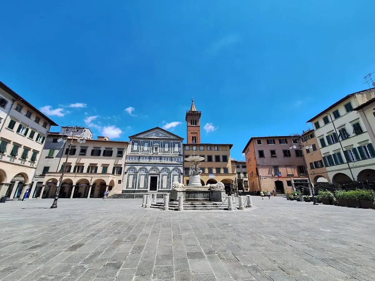 Piazza del Duomo a Empoli: un'idea di cosa vedere in un giorno, con la chiesa, la fontana e i palazzi storici sotto un cielo azzurro.
