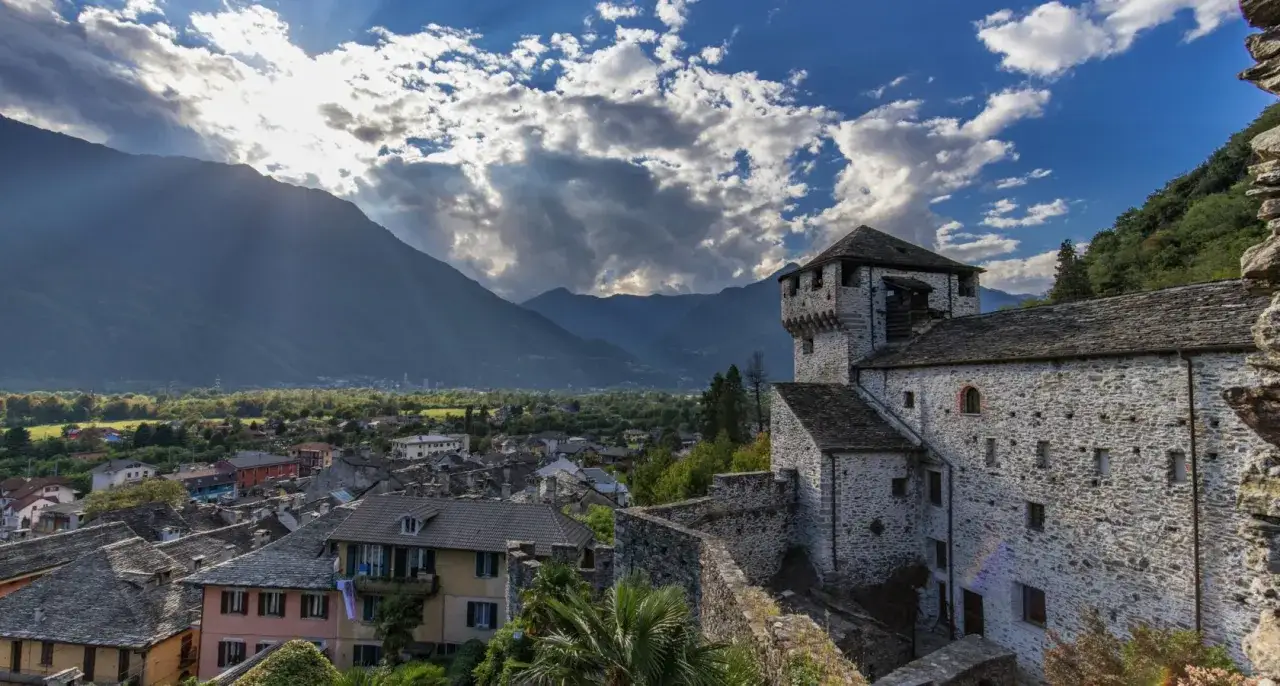 Castello di Bellinzona, un vero spettacolo da vedere, domina il borgo con le sue mura di pietra e le torri imponenti, incorniciato da montagne maestose e un cielo drammatico.