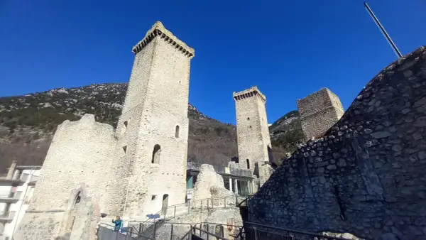 Torri medievali a Pettorano sul Gizio, con montagne sullo sfondo e cielo azzurro.