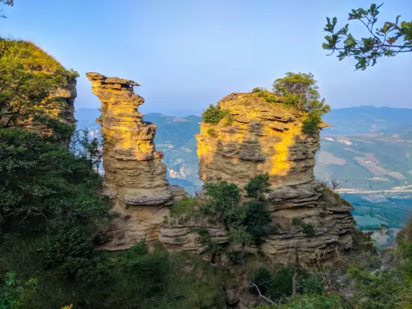 Formazioni rocciose suggestive illuminate dal sole, un paesaggio mozzafiato che ricorda le tappe del cammino della Via degli Dei.
