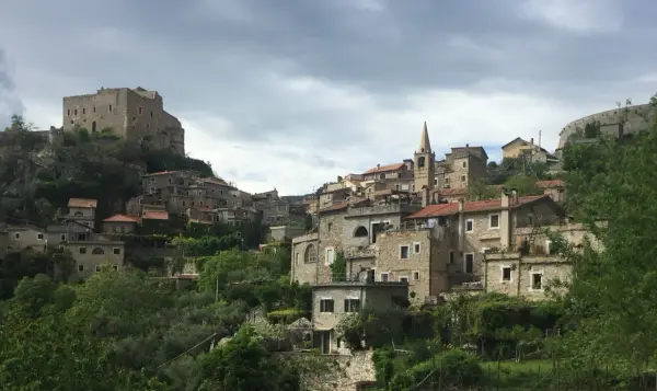 Borgo medievale di Castelvecchio di Rocca Barbena, con case in pietra e un castello in cima alla collina.