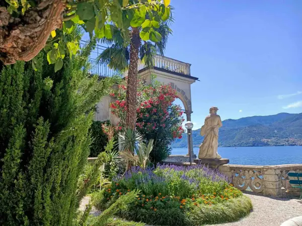 Giardino fiorito con statua e lago sullo sfondo, un angolo incantevole del varenna centro storico.