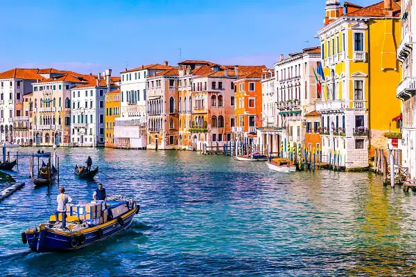 Gondole e vaporetti sul Canal Grande, un assaggio di cosa vedere a Venezia in due giorni. Palazzi colorati e acqua scintillante.