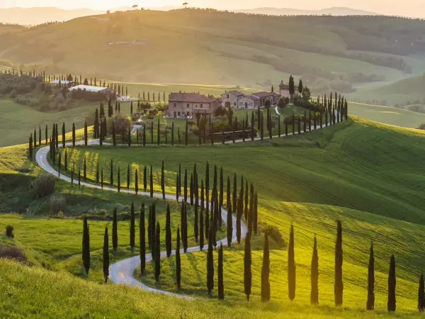 Un sogno per un tour Toscana 3 giorni: colline verdi, cipressi e un casale al tramonto.