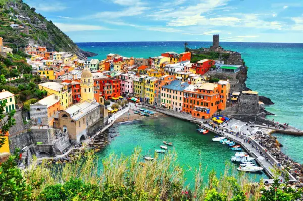 Le Cinque Terre, un gioiello colorato aggrappato alla costa, con case vivaci che si affacciano sul mare turchese e barche che ondeggiano nel porto.