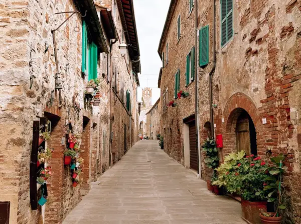 Un vicolo fiorito a Campagnatico, con case in pietra e persiane verdi. Un luogo incantevole da scoprire, tra scorci pittoreschi e storia.
