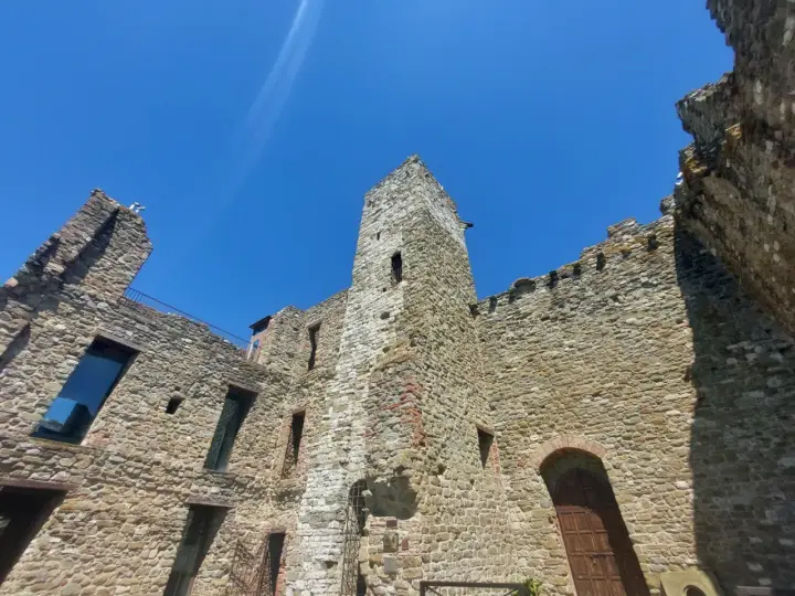 Rovine di un castello nel centro storico di Passignano sul Trasimeno, con mura in pietra e cielo azzurro.