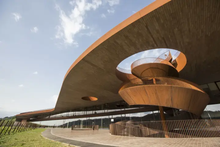 Architettura moderna di cantine toscana famose, con scale a chiocciola in corten e ampie vetrate che riflettono il paesaggio collinare.