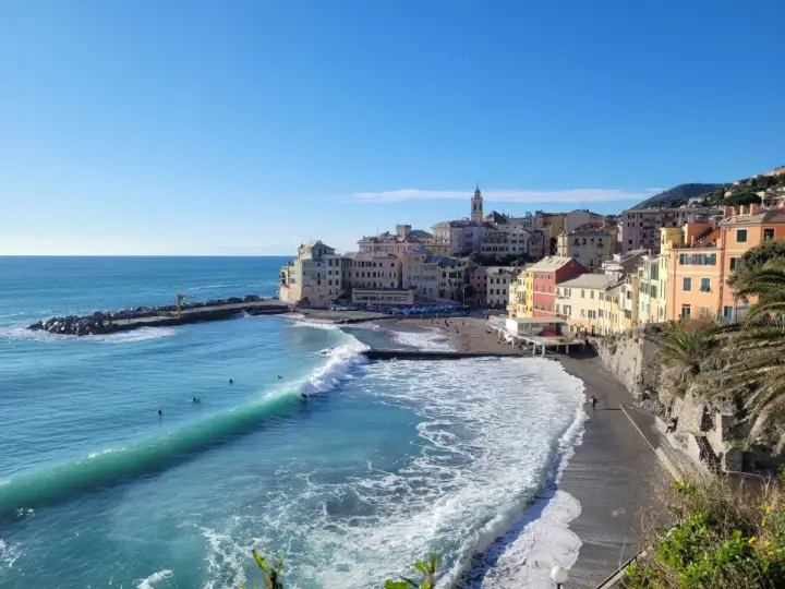 Colorati borghi medievali vicino a Genova, con onde turchesi che si infrangono sulla spiaggia di ciottoli.