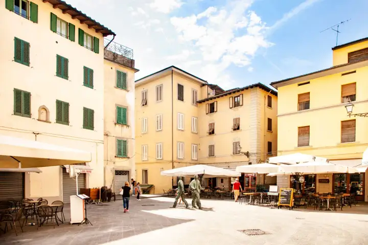 Piazza con edifici storici e tavolini all'aperto, ideale per scoprire cosa vedere a Pistoia in un giorno.